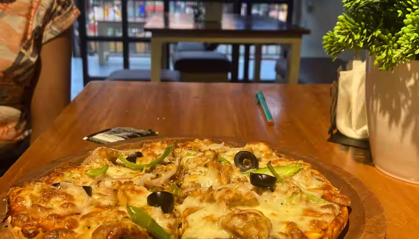 A beautifully presented pizza and refreshing drinks at an open-air café in Lonavala, surrounded by lush greenery and elegant decor