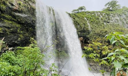 Lush green Khandi Waterfalls flowing through rocky terrain during monsoon season in Maharashtra.