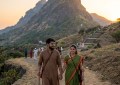Couple walking at dawn on rural path circling Girnar mountain, soft sunrise light, documentary travel photography style,