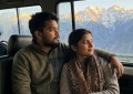 Young Indian couple in shared taxi looking out at snow-capped Kashmir peaks, golden hour light, candid travel moment, wa