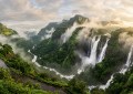 Tamhini Ghat waterfalls in full monsoon flow, mist rising through green mountains, morning golden light, wide landscape