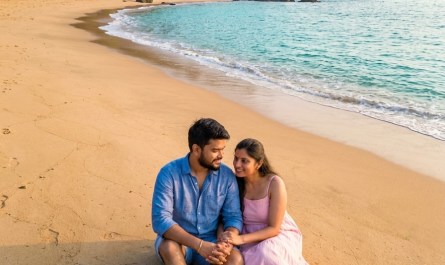 Aerial view of Cola Beach lagoon at sunrise, turquoise water meeting golden sand, couple sitting by the shore, soft morn