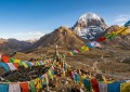 Mount Kailash north face with prayer flags in foreground, clear blue sky, dramatic Tibetan plateau landscape, golden hou