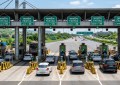 Highway toll booth with multiple FASTag lanes, clear signage, bright daylight, cars passing through, realistic Indian hi