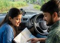 Young couple checking paper map inside car parked on rural Maharashtra road, morning light, dashboard visible, green hil