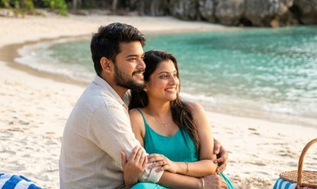 Secluded Cola Beach lagoon at golden hour, turquoise water meeting sand, couple sitting by shore, warm natural light, pe