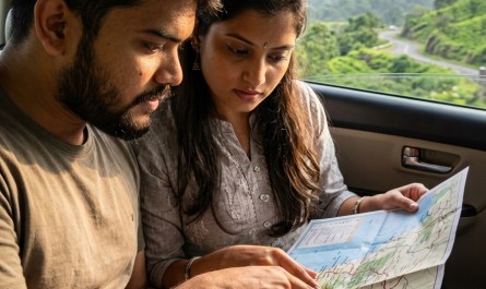 Young Indian couple checking paper map inside car on scenic Western Ghats highway, natural window light, candid travel m