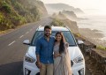 Young Indian couple standing beside car on misty coastal highway, morning golden light, scenic Maharashtra coastline bac