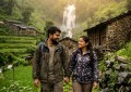 Couple walking through misty village waterfall with lush green mountains, monsoon fog, golden hour soft light, candid tr