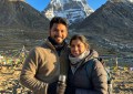 Indian couple standing at Mount Kailash base, clear blue sky, snow-capped peaks, golden hour light, wide-angle travel ph